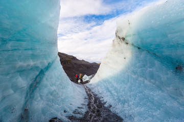 Hiker walking pass ice wall during hiking on glacier, Solheimajokull