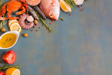 Raw fresh fish variety on blue wooden background with copy space.