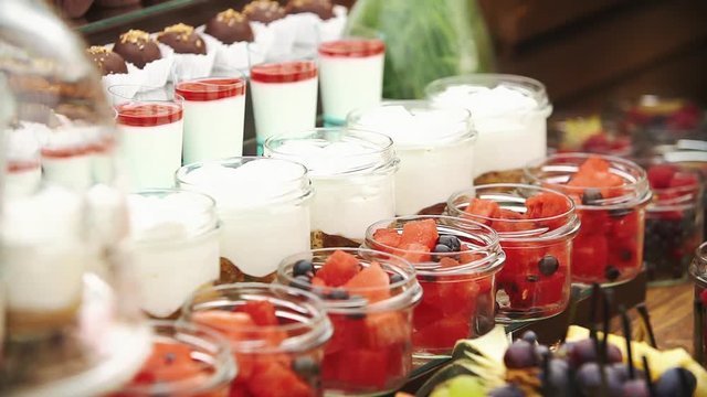 Someone serves fruits in glass bowls on the candy bar
