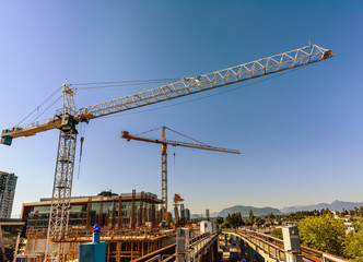 Fototapeta na wymiar tower, building cranes, iron fittings of buildings under construction, scaffolding, against the backdrop of deep skies and mountains