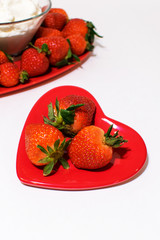 Small heart plate in front with strawberries bigger one behind.