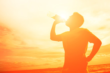 silhouetteof a man drinking water on the freedom beach. healthy concept