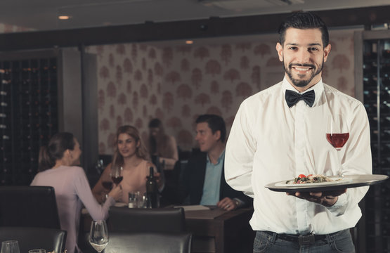 Adult waiter with tray welcoming to restaurant