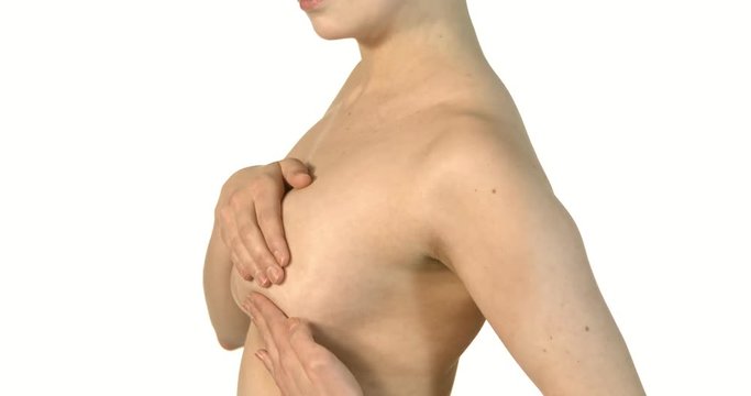 Close-up of young shirtless woman examining her breasts.
