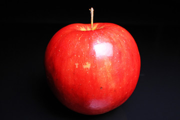 Red shiny whole apple on black reflective studio background. Isolated black shiny mirror mirrored background for every concept.