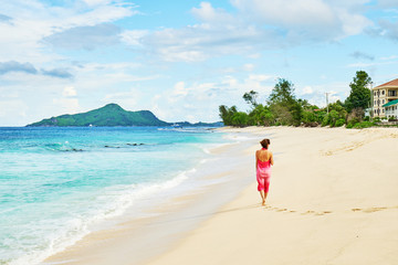 Woman with sarong walking on beach Anse Nord Est at Seychelles, Mahe