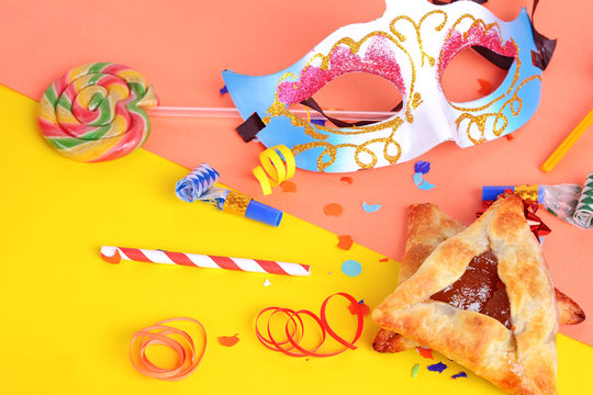 Purim background with carnival mask, party costume and hamantaschen cookies.