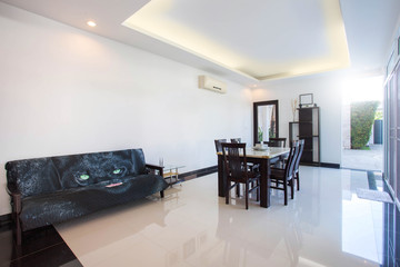 Luxury interior design in living room of pool villas. Airy and bright space with high raised ceiling and wooden dining table