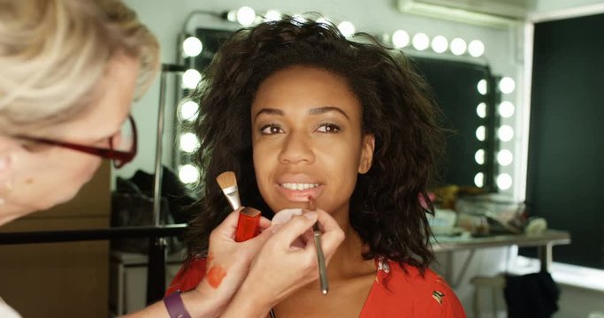 4K Makeup artist preparing beautiful model in the dressing room before a shoot