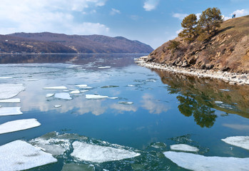 Spring ice drift on Baikal Lake. People admire the white ice on the blue water from the high Bank at the source of the Angara River