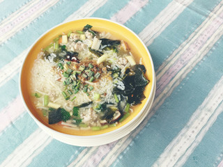 rice soup with vegetables, chickenin and pork in white bowl. Thai style food.