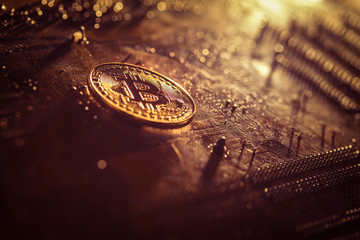 Golden bitcoin token lying on a computer motherboard 