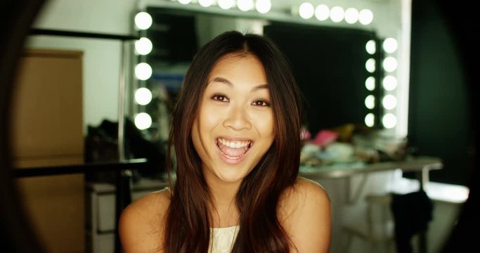 4K Portrait beautiful Asian model pulling faces at the camera. Backstage at fashion shoot or TV studio. Slow motion.