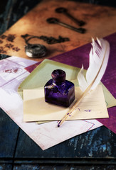 Retro still life. Inkwell,  pocket watch on a chain and feather pen on the background old letters...