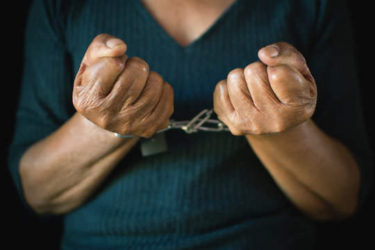 Close-up old hands of woman and chain on black background, Concept no freedom