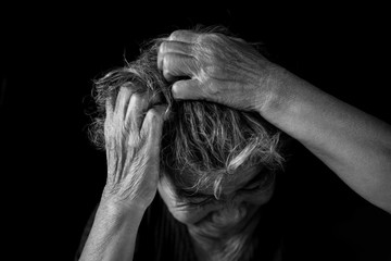 Old woman felt a lot of anxiety about hair loss and itching dandruff issue on black background,...