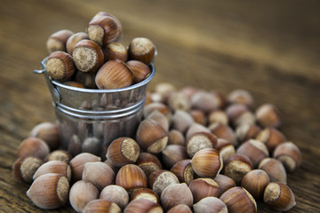 Bucket with hazelnut on a wooden background