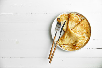 Overhead image of pancakes in white plate on wooden table with space left for text