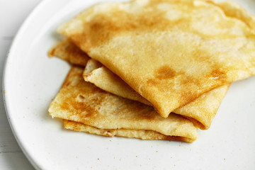 Macro shot of french crepes stacked in white plate