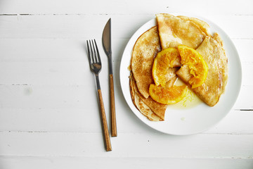 Overhead image of pancakes with orange confitur in white plate on wooden table with space left for text