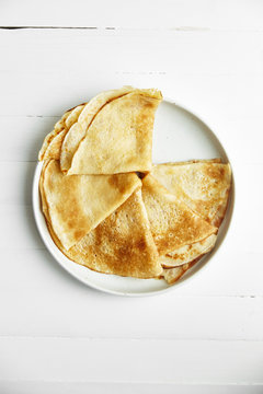 Overhead image of pancakes in white plate on wooden table