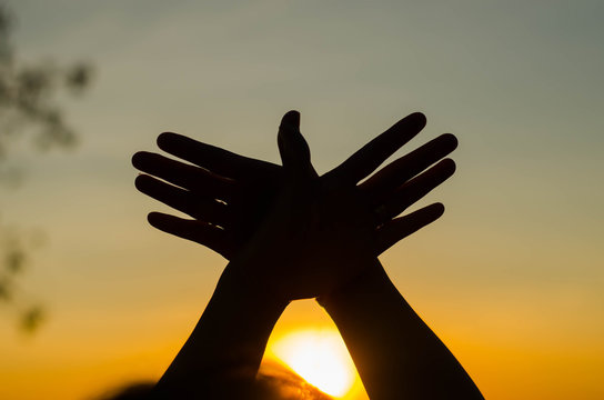 The silhouette of a girl is holding a symbolic hand in a beautiful sunset.