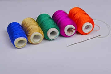 Colorful bobbins of thread with needle