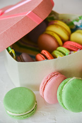 multicolored macaroons in a heart shaped gift box on a white background