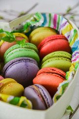 multicolored macaroons in a heart shaped gift box on a white background