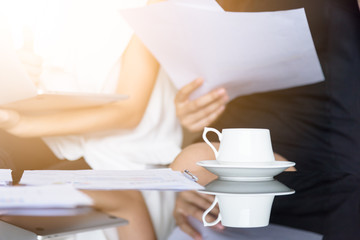 A asain businesswoman has drinking a cup of coffee with workmate together in the office.
