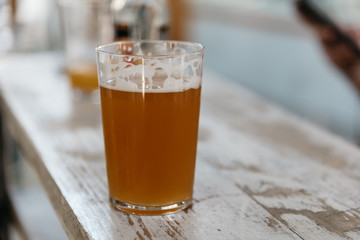 Close up of glass of cold beer on old wooden white painted table