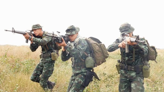 Soldiers team holding gun forward to attack enemy at fields. 