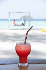 watermelon smoothie  on wooden table with happy couple on swing  background.  Lipe island,Thailand