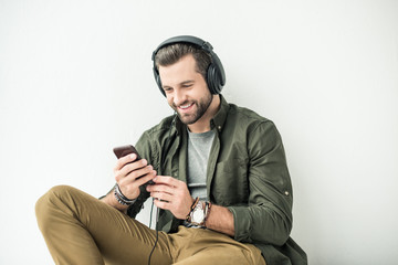 handsome smiling man listening music with smartphone isolated on white