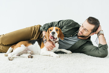 handsome man lying on carpet with cute beagle isolated on white