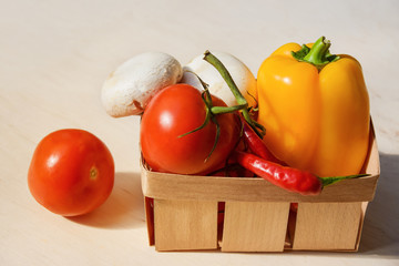 .Fresh seasonal vegetables in a basket on a wooden table.
