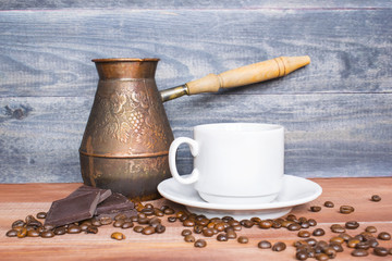 Turkish coffee pot, cup and beans on the wooden table.