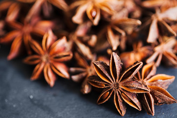 Anise stars closeup in wooden bowl on dark background