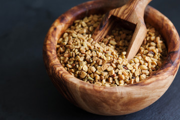 Fenugreek seeds in wooden bowl, spice, culinary ingredient copy space