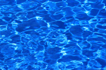 Blue pool water with medium ripples and very small waves in the sun
