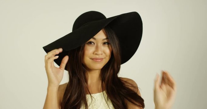 4K Beautiful Asian woman posing with wide brimmed hat on white background. Slow motion.