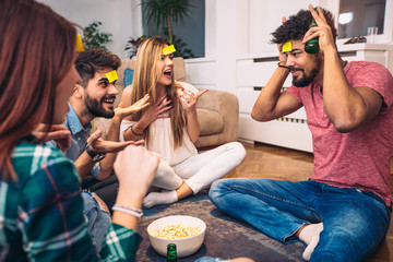 Happy friends playing game guess who and having fun at home