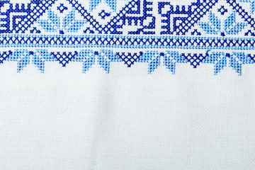Traditional Ukrainian ornament embroidered with a cross on a linen cloth close-up. Copy space