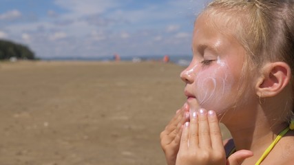 The girl apply sunscreen to face and body. The girl squeezes the sunscreen into her palm and puts...
