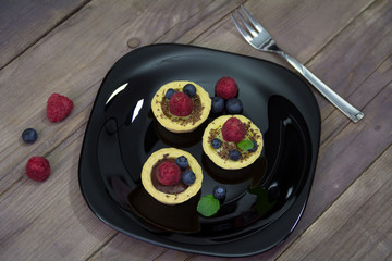 Raspberries and blueberry cupcakes on a  plate.Wooden background