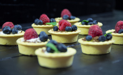Raspberries and blueberry cupcakes on a  plate.Wooden background