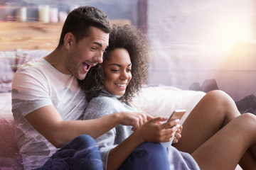 So hilarious. Joyful nice delighted man pointing at the smartphone screen and laughing while seeing a funny picture