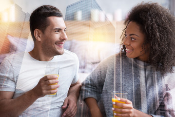 Healthy lifestyle. Joyful positive delighted couple holding glasses and looking at each other while drinking orange juice