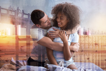 Perfect relationships. Joyful nice handsome man embracing his girlfriend and smiling while expressing his feeling towards her