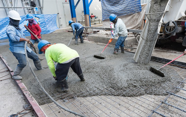 Workers at the construction site placing concrete slab